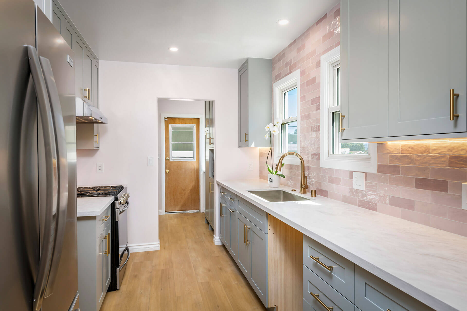 Remodelação de cozinha com contraste de móveis verde e frontal de parede rosa