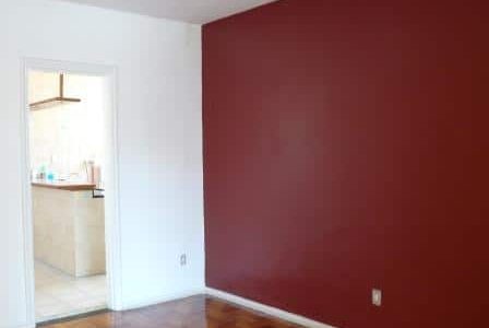 Pintura em sala com paredes branca e vermelha.